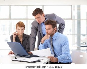 Tre professionelle kolleger analyserer virksomhedsoplysninger på en bærbar computer.